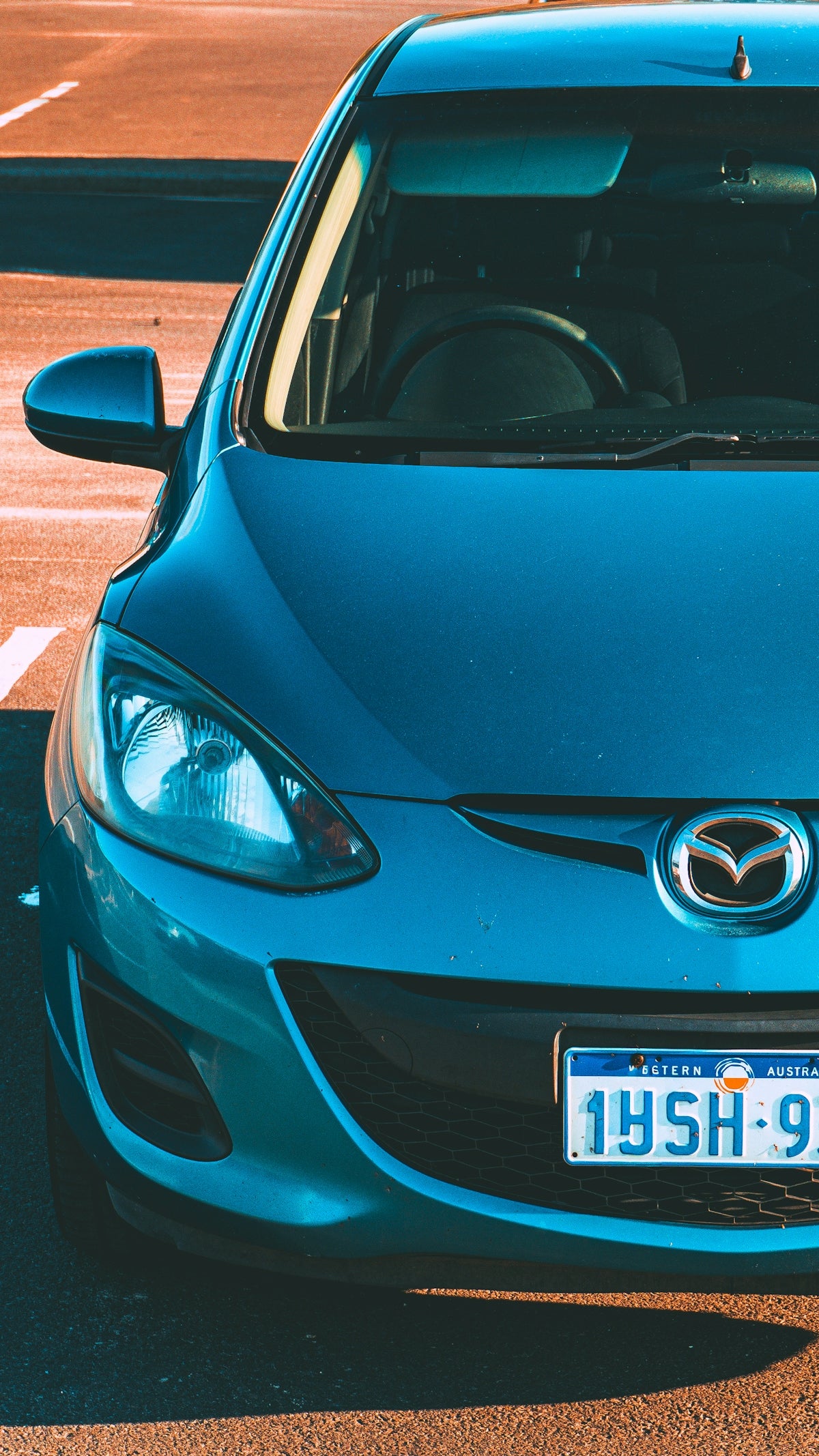 Blue car parked on asphalt with white lines