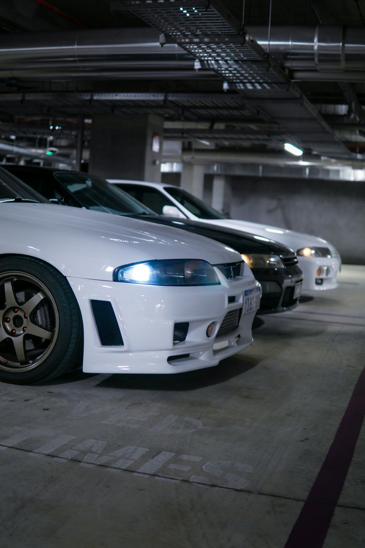 Three sports cars parked in a dimly lit garage
