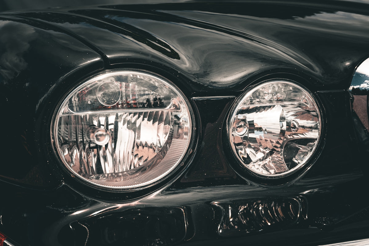 Front view of two shiny headlights on a dark car.