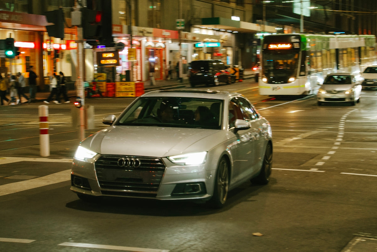 An audi drives through a city at night.
