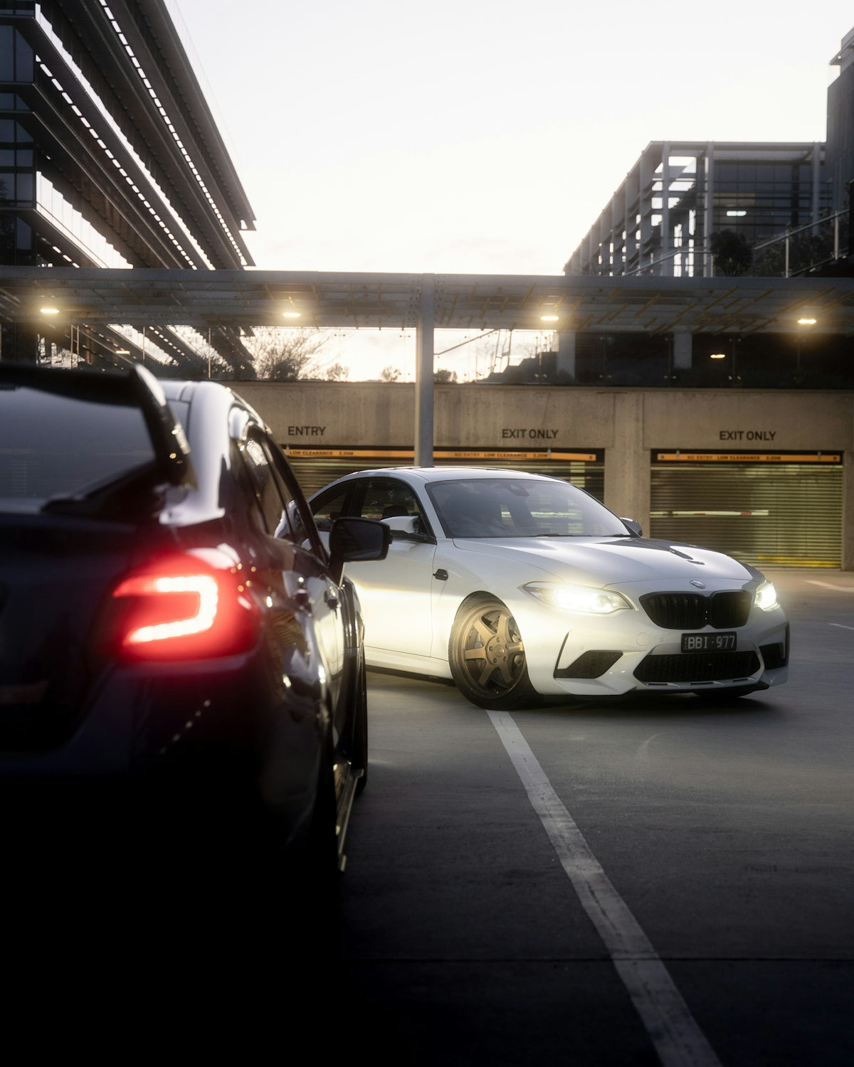 Two cars parked in a lot at dusk.