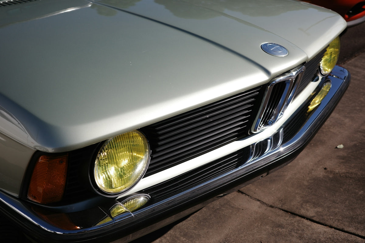 Silver vintage car with yellow headlights and chrome grille