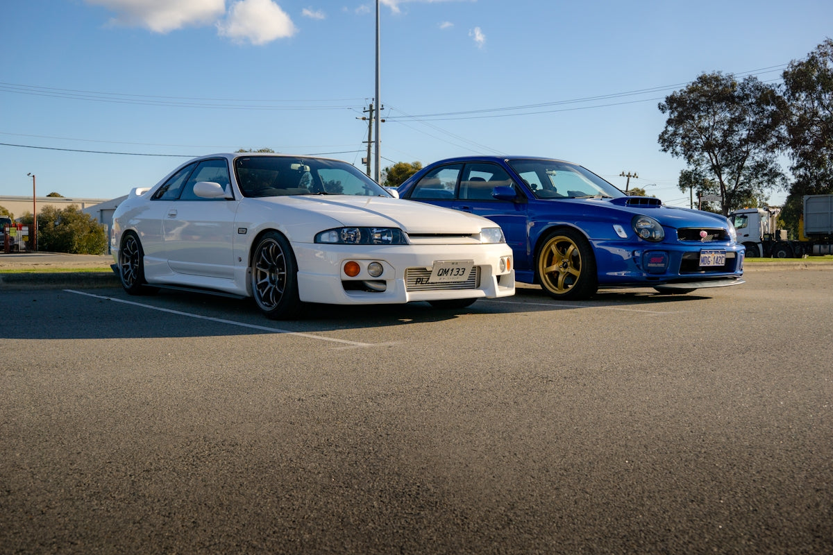 Two white and blue sports cars parked on asphalt.