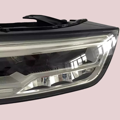 Reconditioned Audi Q3 LED headlight, clear lens, close-up on neutral background